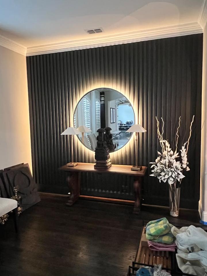 Backlit black slat wall with round mirror